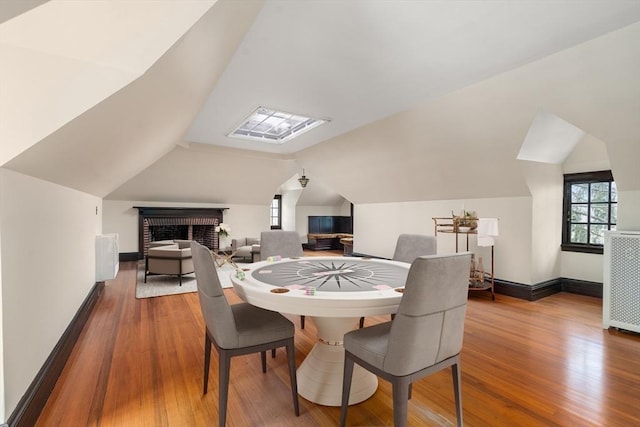 dining area with radiator heating unit, lofted ceiling, a brick fireplace, and hardwood / wood-style floors