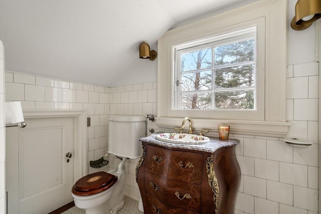 bathroom featuring tile walls, vanity, vaulted ceiling, and toilet