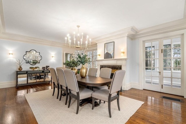 dining room featuring a premium fireplace, a chandelier, crown molding, and wood-type flooring