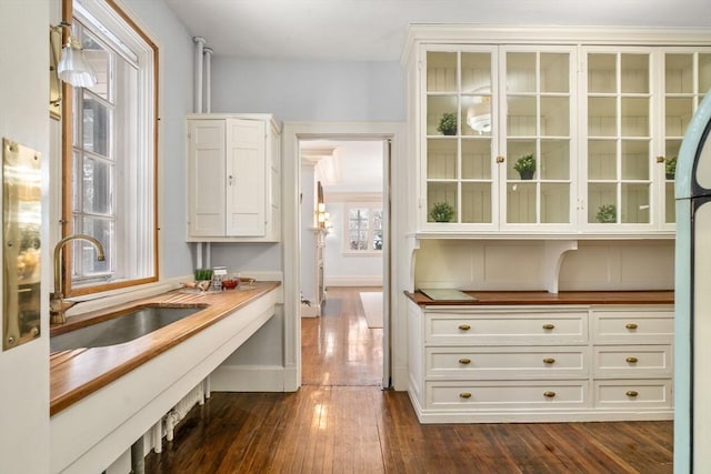 bar featuring sink, white cabinetry, and dark hardwood / wood-style floors