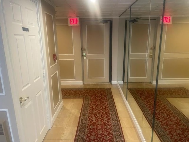 hallway featuring light tile patterned floors and a decorative wall