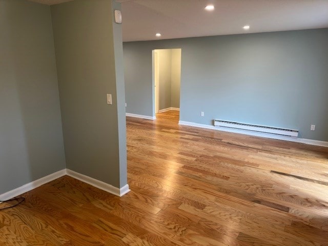 unfurnished room with a baseboard radiator and light wood-type flooring