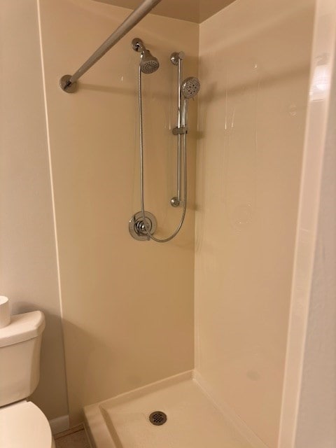 bathroom featuring tiled shower and toilet