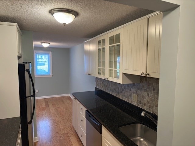 kitchen featuring sink, light hardwood / wood-style flooring, backsplash, white cabinets, and appliances with stainless steel finishes