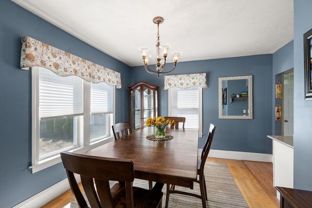 dining room featuring light wood-type flooring, baseboards, and a notable chandelier