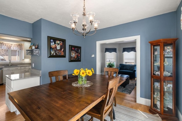 dining room featuring baseboards, an inviting chandelier, and light wood-type flooring