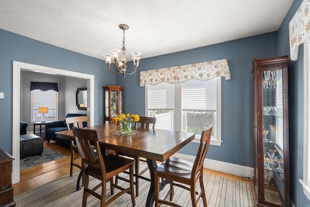 dining area featuring baseboards, wood finished floors, and a notable chandelier