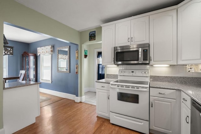 kitchen with appliances with stainless steel finishes, decorative backsplash, baseboards, and white cabinets