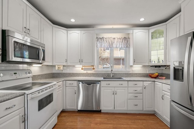 kitchen with appliances with stainless steel finishes, a sink, light countertops, white cabinetry, and recessed lighting