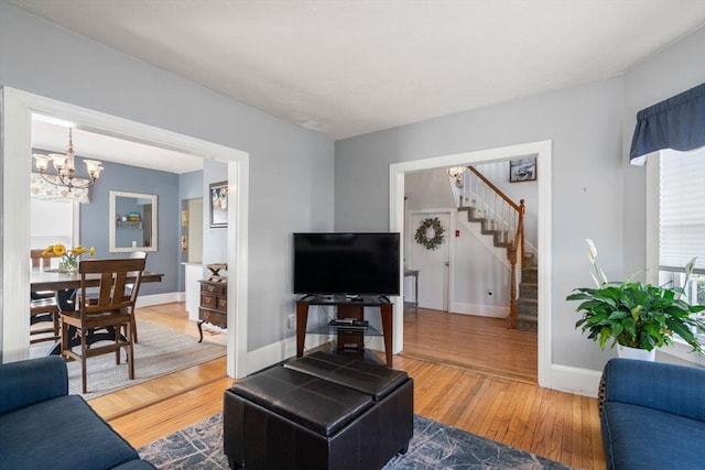 living room featuring stairway, baseboards, an inviting chandelier, and wood finished floors