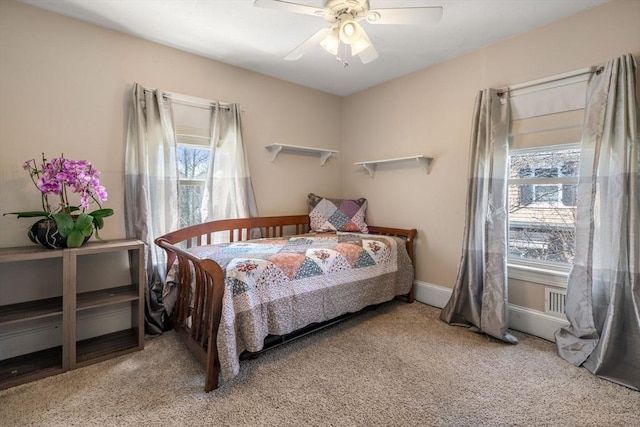carpeted bedroom featuring multiple windows and ceiling fan