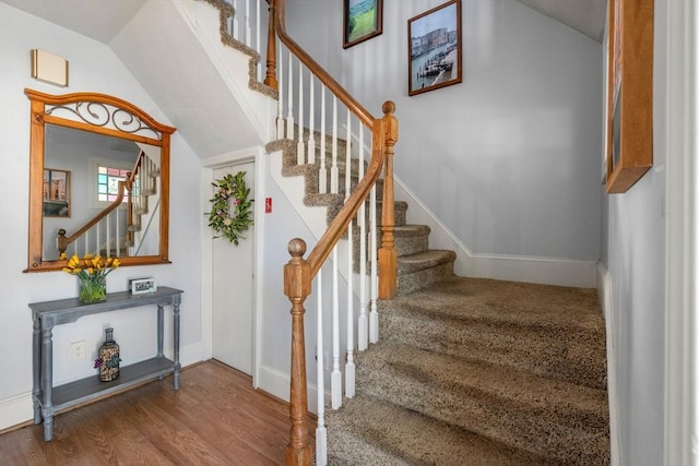 stairs with baseboards, wood finished floors, and vaulted ceiling