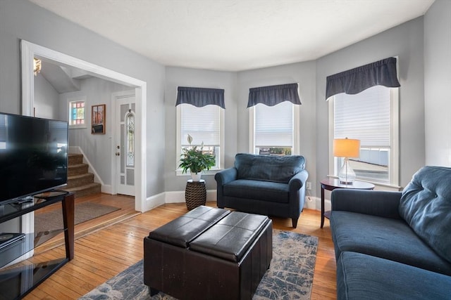 living area featuring stairway, baseboards, and light wood finished floors