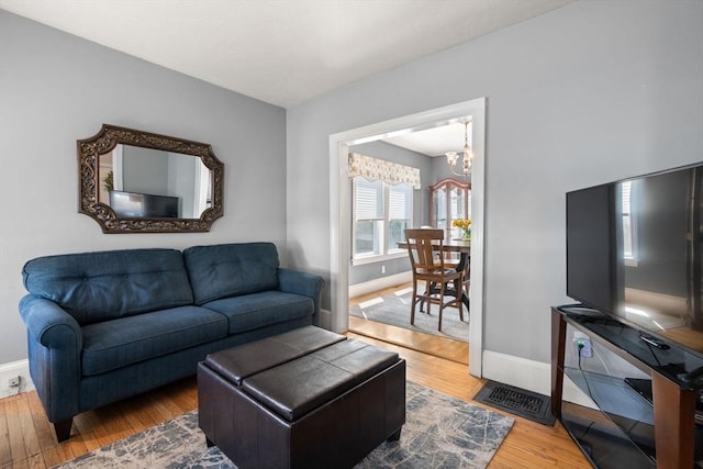 living area featuring baseboards, an inviting chandelier, and wood finished floors