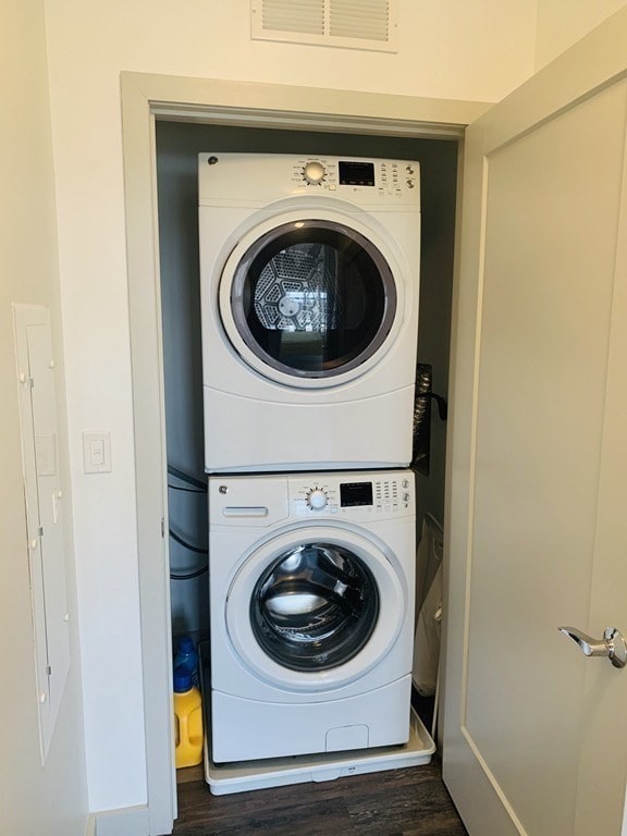 laundry room with stacked washer / dryer and dark hardwood / wood-style floors