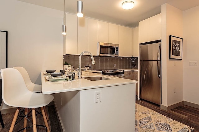 kitchen featuring stainless steel appliances, sink, dark hardwood / wood-style floors, kitchen peninsula, and a breakfast bar