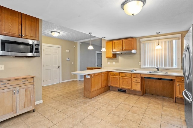 kitchen featuring stainless steel appliances, a peninsula, a sink, under cabinet range hood, and decorative light fixtures
