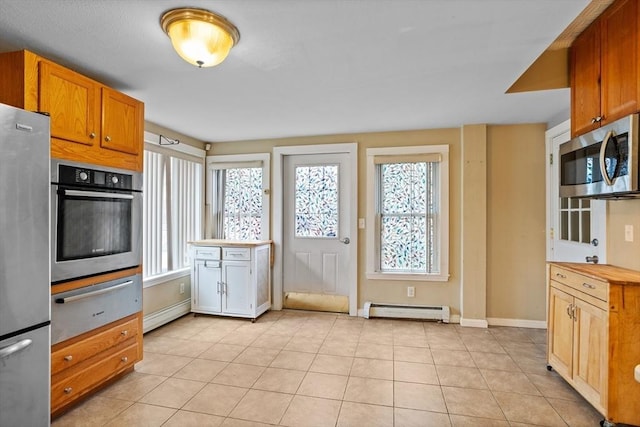 kitchen with appliances with stainless steel finishes, a baseboard radiator, a warming drawer, and plenty of natural light
