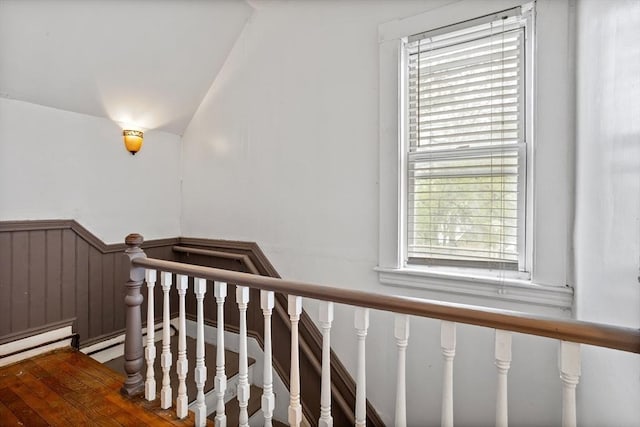 stairs featuring vaulted ceiling and a wainscoted wall