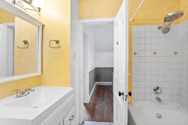 bathroom featuring wainscoting, bathing tub / shower combination, wood finished floors, and vanity