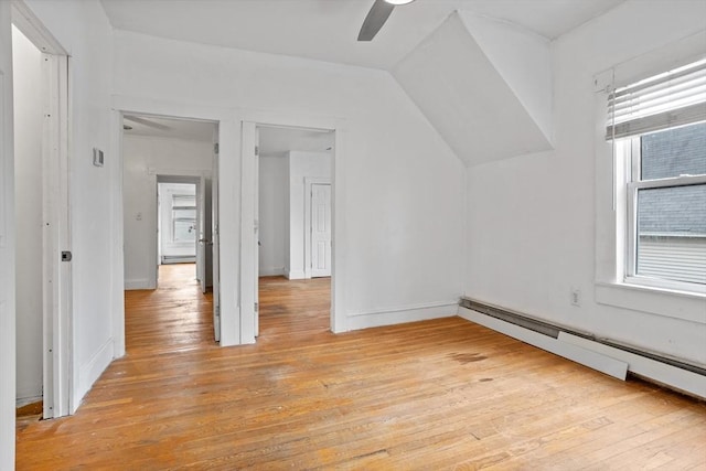 additional living space with ceiling fan, light wood-style flooring, a baseboard heating unit, a baseboard radiator, and vaulted ceiling