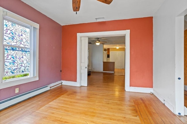 spare room with ceiling fan, a baseboard radiator, and light wood finished floors