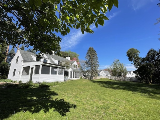 view of yard featuring fence and a sunroom