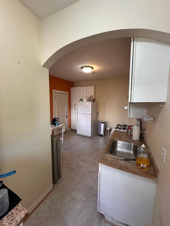 1269 Commonwealth Ave Unit 2, Boston, MA 02134 - kitchen with arched walkways, freestanding refrigerator, a sink, white cabinets, and dark countertops