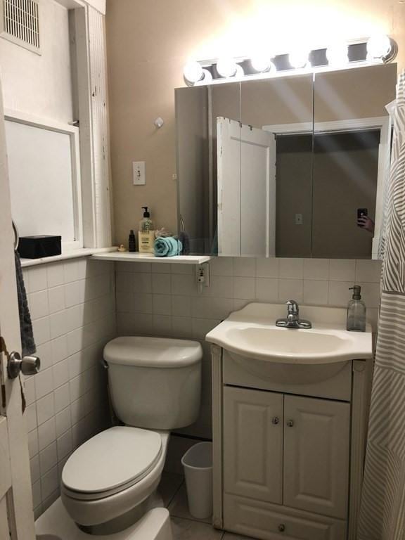 1269 Commonwealth Ave Unit 2, Boston, MA 02134 - bathroom with tile walls, toilet, vanity, and tile patterned floors