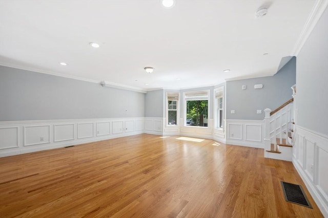 33 Oval Rd Unit 2, Quincy, MA 02170 - unfurnished living room featuring crown molding, stairs, a decorative wall, light wood finished floors, and wainscoting
