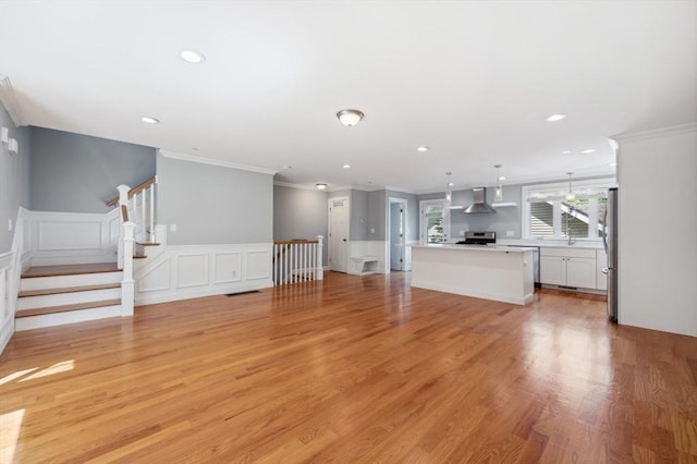 33 Oval Rd Unit 2, Quincy, MA 02170 - unfurnished living room featuring crown molding, light wood-style floors, recessed lighting, a decorative wall, and stairs