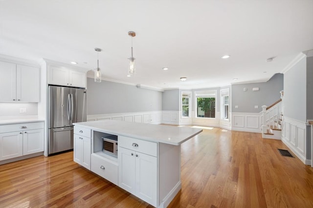 33 Oval Rd Unit 2, Quincy, MA 02170 - kitchen featuring freestanding refrigerator, crown molding, light countertops, a decorative wall, and built in microwave