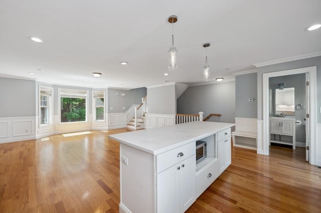 33 Oval Rd Unit 2, Quincy, MA 02170 - kitchen with ornamental molding, a decorative wall, hanging light fixtures, white cabinetry, and stainless steel microwave