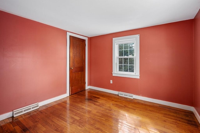 empty room with visible vents, baseboards, and hardwood / wood-style flooring