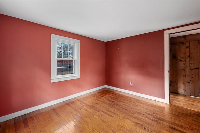 empty room with baseboards and hardwood / wood-style flooring