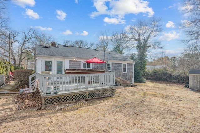 back of property with a chimney, french doors, a shingled roof, and a deck