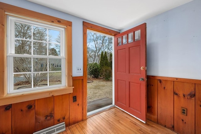 entrance foyer with a wainscoted wall, light wood-style floors, visible vents, and wooden walls