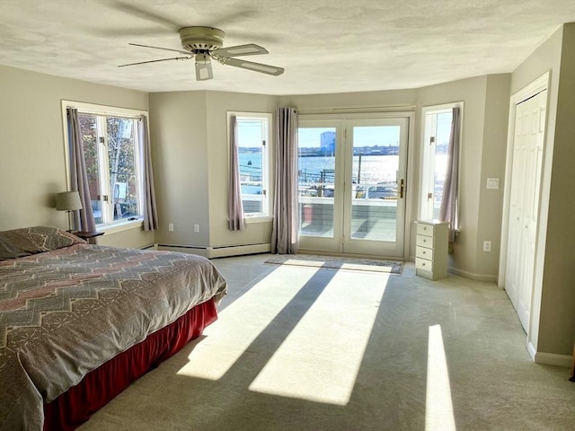 bedroom featuring multiple windows, a water view, access to outside, and ceiling fan