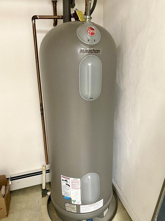 utility room featuring water heater and a baseboard radiator