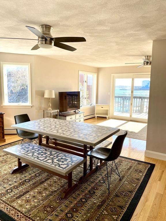 dining space featuring a baseboard heating unit, wood-type flooring, and ceiling fan