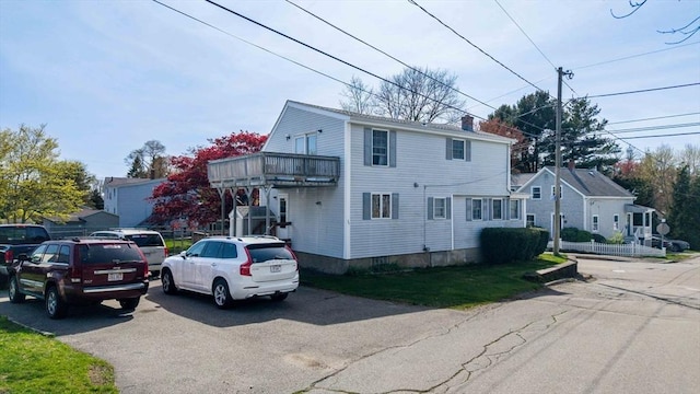 view of front of house featuring a chimney and a balcony