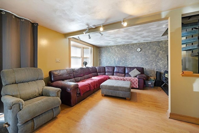 living room featuring rail lighting, light wood-style floors, wallpapered walls, and an accent wall