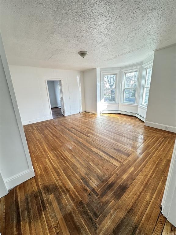 391 Pleasant St, Holyoke, MA 01040 - interior space featuring baseboards, a textured ceiling, and wood-type flooring