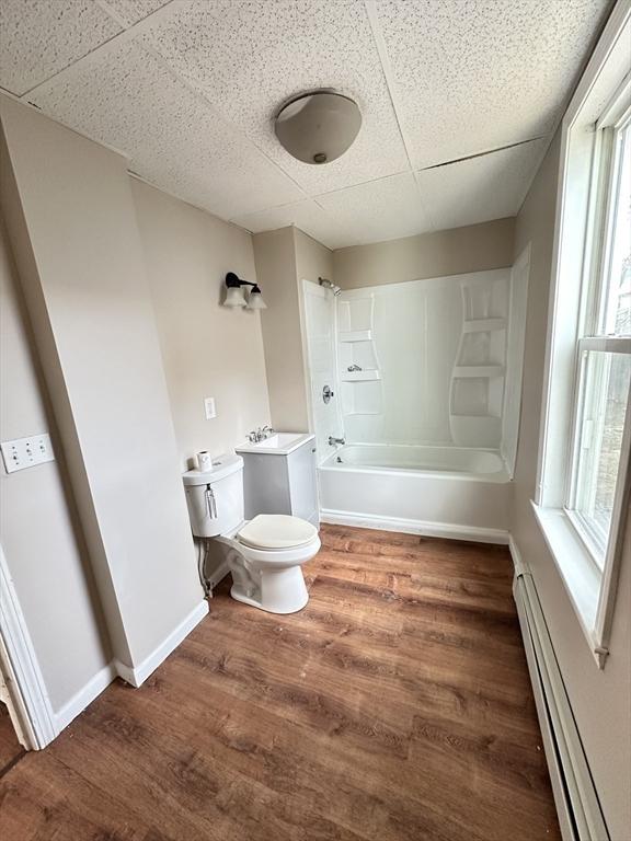 391 Pleasant St, Holyoke, MA 01040 - bathroom featuring baseboard heating, wood finished floors, shower / bathtub combination, and toilet