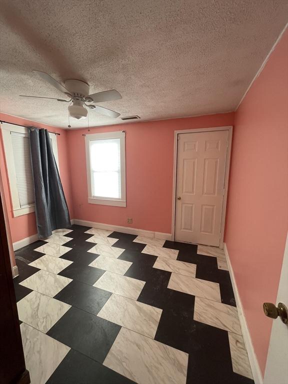 empty room with a textured ceiling and ceiling fan