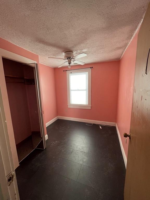 unfurnished bedroom featuring a textured ceiling, a closet, and ceiling fan