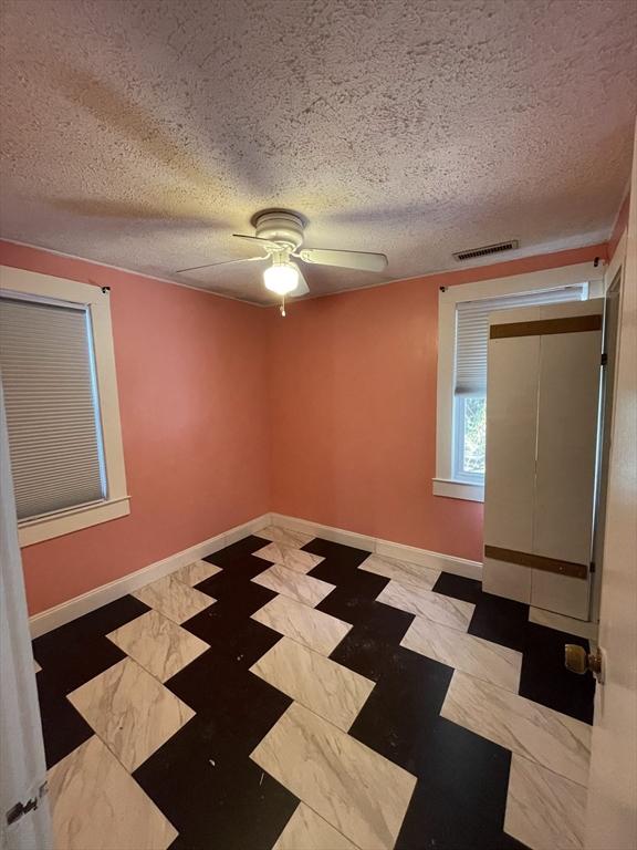 unfurnished room with a textured ceiling and ceiling fan