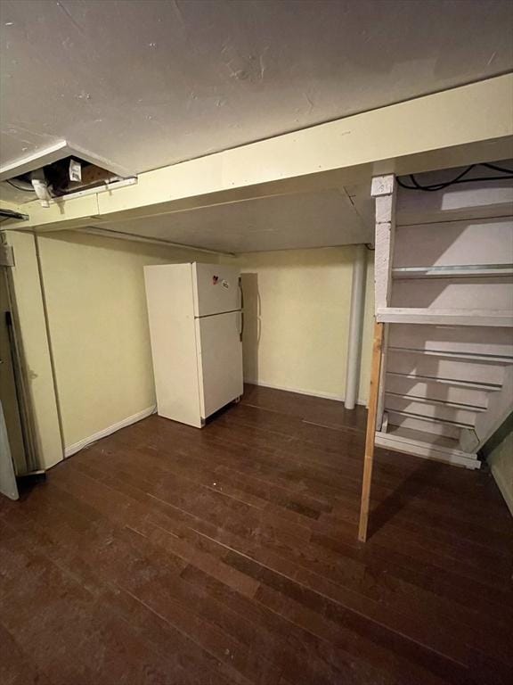 basement with dark wood-type flooring and white refrigerator