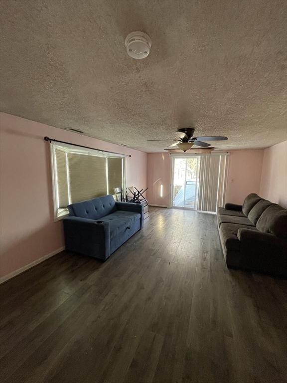 living room featuring ceiling fan, dark wood-type flooring, and a textured ceiling