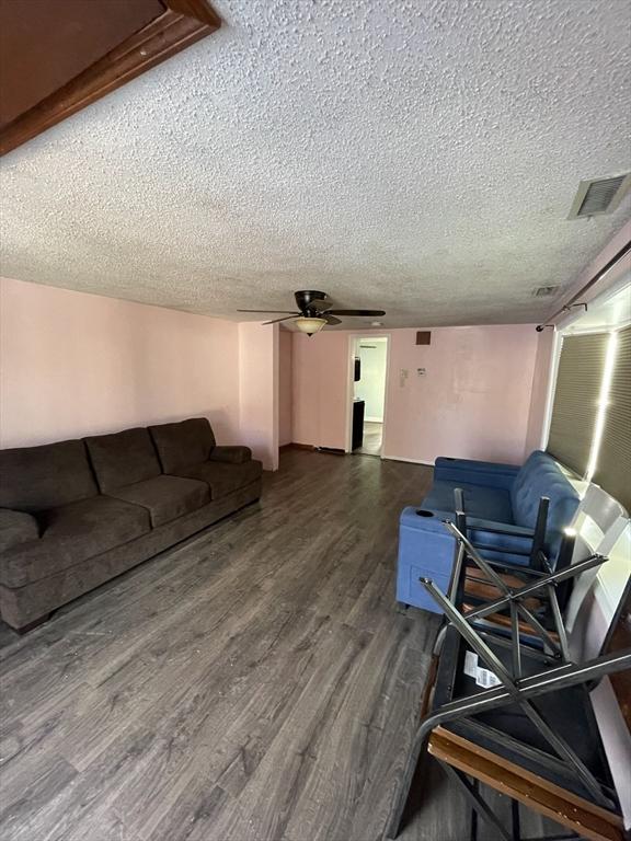 living room with hardwood / wood-style flooring, ceiling fan, and a textured ceiling